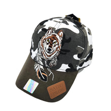 A baseball cap with a black, white, and gray camouflage pattern on the crown, featuring a large embroidered wolf with a feather headdress on the front. The visor is solid dark brown and has a brown leather patch reading 'NATIVE PRIDE' and a holographic sticker.
